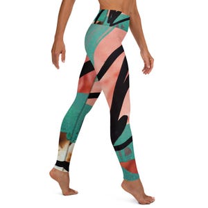 May include: High-waisted leggings with an abstract design. The leggings feature a mix of colors, including teal, coral, and black. The design has bold, black brushstrokes and geometric shapes. The leggings are made of a stretchy material and are suitable for yoga or other activities.