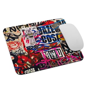 Pode incluir: Um tapete de rato colorido com uma colagem de grafites e adesivos. O tapete de rato apresenta uma variedade de cores, incluindo vermelho, azul, verde, amarelo e preto. O texto "GLASS" é visível no canto inferior direito.