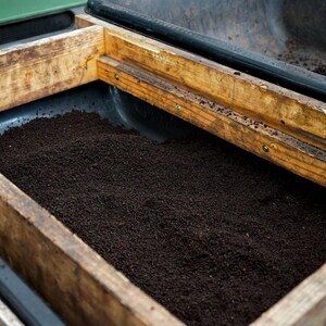 Pure screened worm castings in a black tub with worm shaker frame.