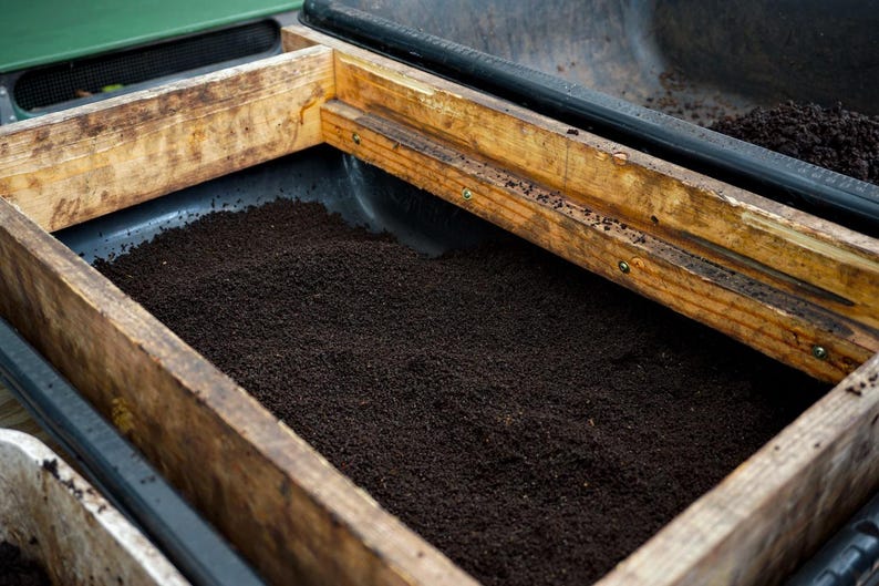 Pure screened worm castings in a black tub with worm shaker frame.
