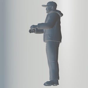 May include: A gray figurine of a person wearing a hooded jacket, a baseball cap, and jeans. The person is standing with their arms crossed and looking to the side.