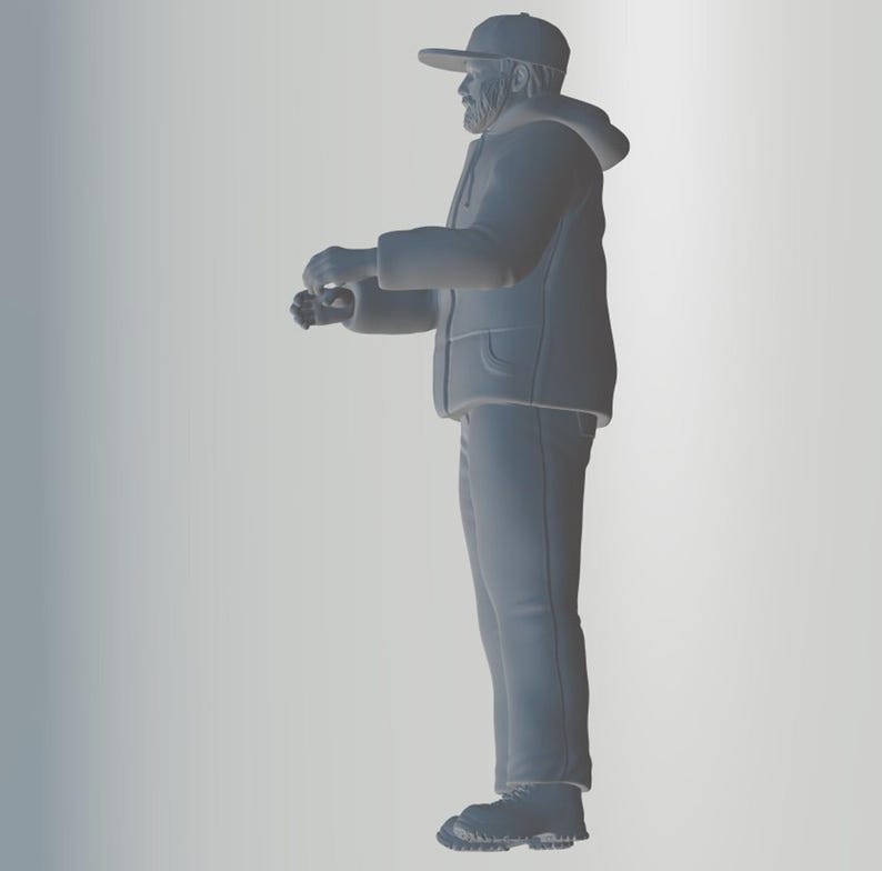 May include: A gray figurine of a person wearing a hooded jacket, a baseball cap, and jeans. The person is standing with their arms crossed and looking to the side.