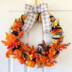 Gran corona de Halloween original hecha a mano con espantapájaros, calabazas, flores otoñales y lazos – Decoración rústica para puerta o centro de mesa.