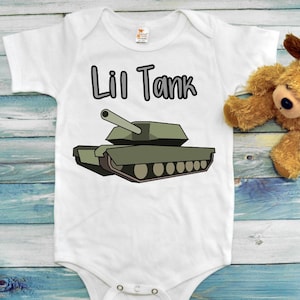 May include: White baby onesie with a green cartoon tank and the text "Lil Tank" printed on the front.