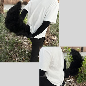 May include: A person wearing a white t-shirt and black pants with a black furry tail attached to their waist.