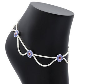 May include: Silver anklet with three blue and red eye charms. The anklet is on a black mannequin foot.