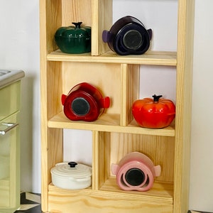 May include: A wooden shelf unit with six compartments, each holding a different colored ceramic pot with a lid. The pots are in shades of green, purple, red, pink, and white.