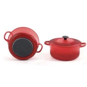 May include: Two red cast iron Dutch ovens with black handles and lids. One oven is shown from the bottom and the other is shown from the side.
