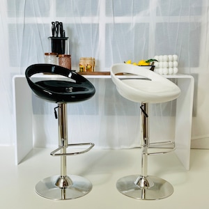 May include: Two adjustable height bar stools with a chrome base and footrest. One stool is black and the other is white.