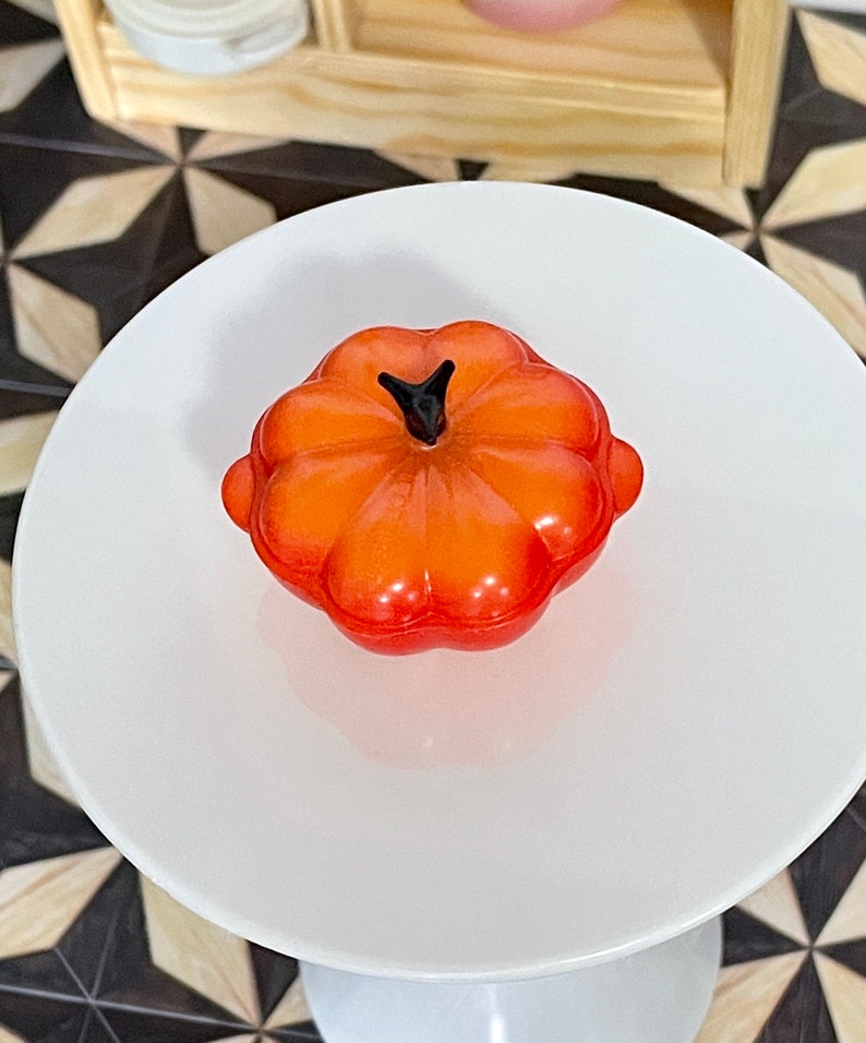 May include: Orange pumpkin-shaped ceramic casserole dish with a black knob on the lid.