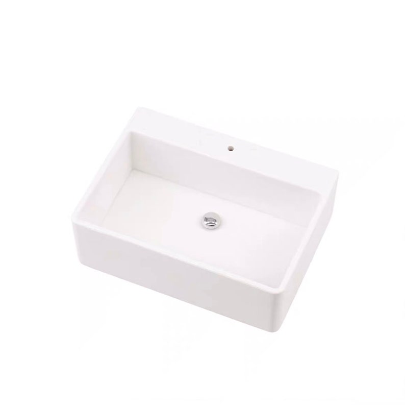May include: White ceramic bathroom sink with a single drain hole and a chrome drain stopper.