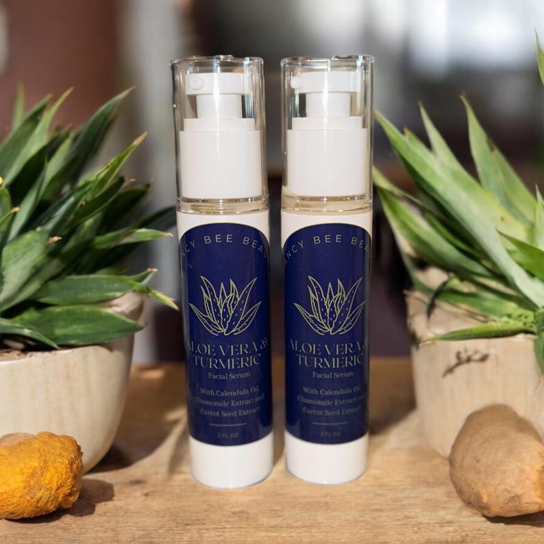 Peut inclure: Deux flacons blancs de s&eacute;rum facial &agrave; l'aloe vera et au curcuma avec des &eacute;tiquettes bleues et dor&eacute;es. Les &eacute;tiquettes pr&eacute;sentent une illustration d'une plante d'aloe vera verte et le texte "Aloe Vera & Turmeric Facial Serum".