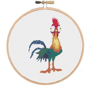 May include: Cross-stitch pattern of a rooster with a red comb, green and blue feathers, and large, wide eyes. The rooster is in a wooden embroidery hoop.