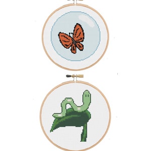 May include: Two cross-stitch embroidery hoops. The top hoop features an orange butterfly inside a blue bubble. The bottom hoop shows a green caterpillar on a green leaf. The brand name "BlancheStitches" is above the hoops.