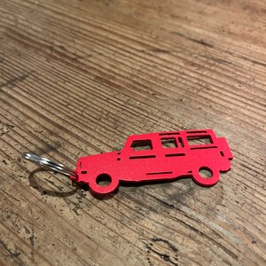 Puede incluir: Llavero de metal rojo con forma de jeep con un anillo plateado.