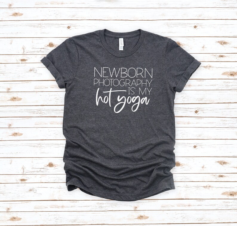 Peut inclure: Un t-shirt gris fonc&eacute; avec le texte "NEWBORN PHOTOGRAPHY IS MY HOT YOGA" imprim&eacute; en blanc.