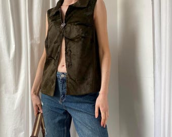 May include: A brown suede vest with a silver button closure and a collared neckline. The vest is sleeveless and has a slightly cropped length.
