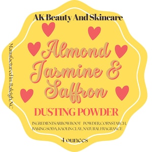 May include: A yellow label with the text "AK Beauty And Skincare" and "Almond Jasmine & Saffron DUSTING POWDER." The label includes pink hearts and lists ingredients and the product size as 4 ounces.