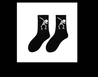 May include: A pair of black socks with a white skeleton design. The skeleton is in a dabbing pose.