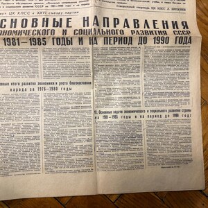 May include: A black and white newspaper headline reads "Основные направления экономического и социального развития СССР на 1981-1985 годы и на период до 1990 года" which translates to "Basic Directions of Economic and Social Development of the USSR for 1981-1985 and for the period until 1990".