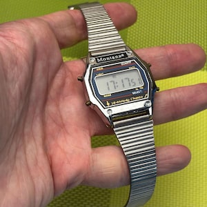 May include: A silver digital wristwatch with a black face and a silver metal strap. The watch face displays the time as 17:17:51 and has the words "Montana" and "16-Melody Chime" printed on it.