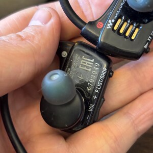 May include: Black Sony Walkman wireless in-ear headphones with a wrap-around neckband. The device features grey silicone ear tips, volume and playlist control buttons, and printed text including the serial number 6793949 and Made in Malaysia.