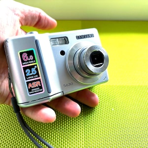 May include: A silver Samsung S630 digital camera with a 6.0 megapixel sensor, a 2.5 inch LCD screen, and ASR (Advanced Shake Reduction).