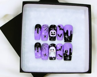 May include: Set of six purple and black Halloween-themed press-on nails with spiderwebs, bats, ghosts, and pumpkins.