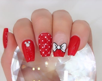 Könnte beinhalten: Rote Sargnagel mit weißen Punkten, einer weißen Schleife mit schwarzem Umriss und einem Strass-Mickey-Maus-Kopf.