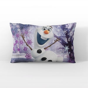 May include: A purple and blue pillow with a white snowman character with black eyes and a black button nose. The snowman is smiling and has its arms outstretched. The background is a purple and blue winter scene with snowflakes.