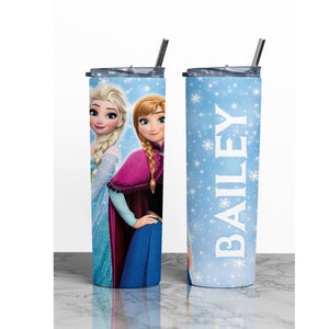 K&ouml;nnte beinhalten: Zwei Edelstahlbecher mit Deckel und Strohhalmen. Ein Becher hat einen blauen Hintergrund mit wei&szlig;en Schneeflocken und den Namen "BAILEY" in wei&szlig;. Der andere Becher zeigt ein Bild von Elsa und Anna aus dem Film Frozen.