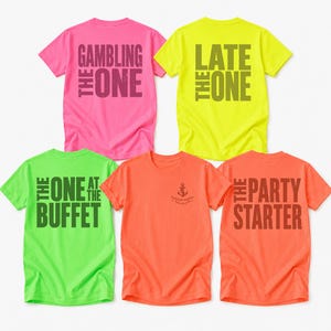 May include: Five short-sleeved t-shirts in neon colors. The pink shirt says THE GAMBLING ONE, the yellow says THE LATE ONE, the light green says THE ONE AT THE BUFFET, the orange has a small anchor logo, and the coral shirt says THE PARTY STARTER.