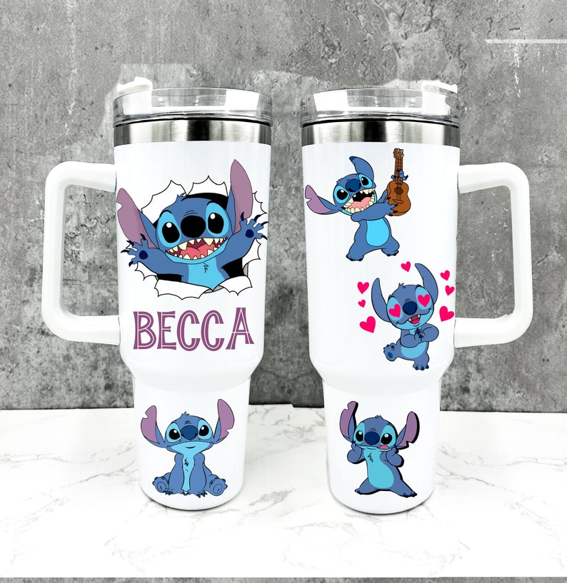 May include: Two white stainless steel travel mugs featuring a blue Stitch character from the Disney film Lilo & Stitch. One mug shows Stitch peeking out of a hole with the name "BECCA" printed below. The other mug depicts Stitch playing a ukulele, Stitch with hearts around his head, and Stitch with his arms crossed.