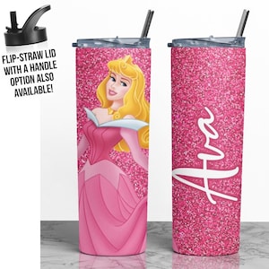 May include: A pink glitter tumbler with a picture of Sleeping Beauty on one side and the name "Ava" on the other side. The tumbler has a black lid with a straw.