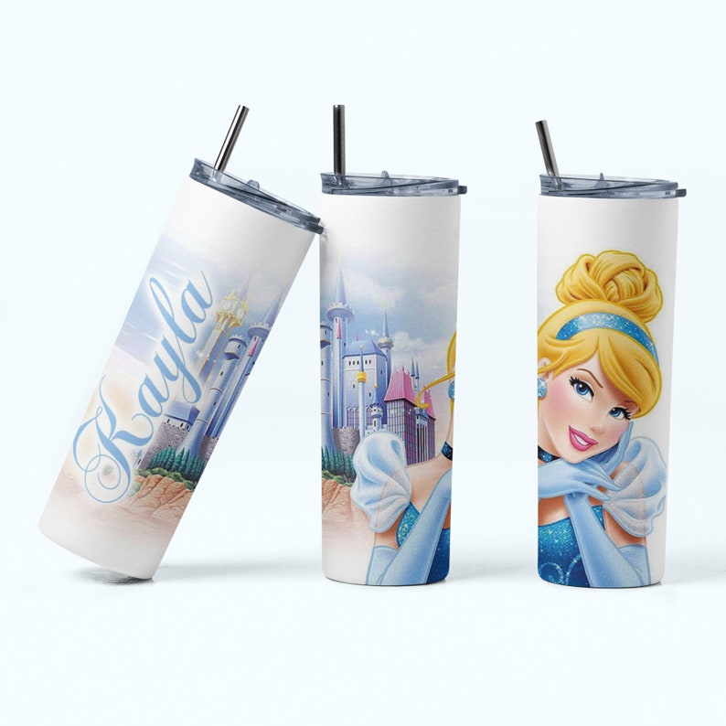 May include: A white stainless steel tumbler with a blue and pink Cinderella design. The tumbler has a straw and the name "Rayla" is written on the side.
