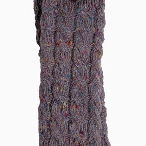May include: A gray knitted leg warmer with a cable knit design and a wooden button closure. The leg warmer is made of a speckled yarn with flecks of color.