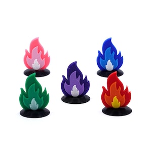 May include: Ten small plastic flame figurines in various colours, including green, pink, blue, purple, orange, and red. Each flame is on a black base.