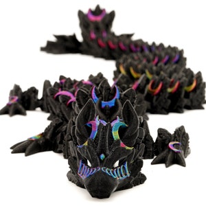 May include: A black dragon figurine with iridescent rainbow accents. The dragon is posed in a crawling position with its head raised and its wings spread out. The figurine is made of a textured material and has a detailed design.