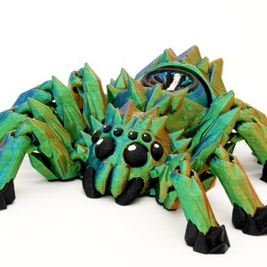 May include: A 3D printed, iridescent green spider with black eyes and legs. The spider has a crystalline texture and is posed in a crawling position.