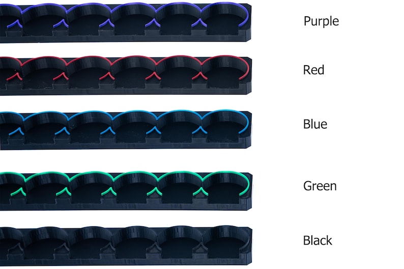 Pode incluir: Cinco filas de suportes de pl&aacute;stico preto com an&eacute;is de diferentes cores. Os an&eacute;is s&atilde;o roxo, vermelho, azul, verde e preto.