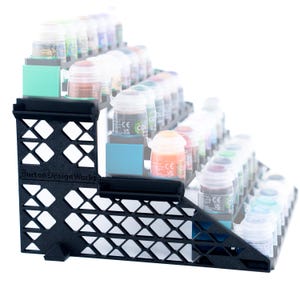 May include: Black plastic paint rack with multiple shelves for storing small paint bottles. The rack is labeled "Burton Design Works".