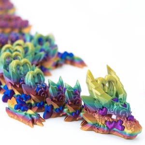 May include: A multi-colored iridescent dragon figurine made of plastic. The dragon is made up of many small, interlocking pieces that form a long, serpentine body. The dragon's head is facing the viewer and has a detailed, intricate design.
