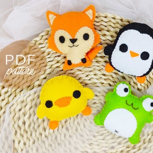 Op de afbeelding: PDF-patroon voor vier vilten dierenknuffels: een vos, een pinguïn, een eend en een kikker. De knuffels lachen allemaal en hebben grote ogen. De vos is oranje, de pinguïn is zwart-wit, de eend is geel en de kikker is groen.