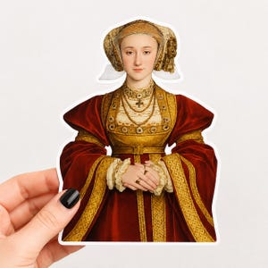 Könnte beinhalten: Ein gestanzter Aufkleber mit dem Porträt einer Person in einem tiefroten Samtkleid mit Goldbesatz, einem cremefarbenen Oberteil und einer passenden goldenen Kopfbedeckung. Die Figur trägt mehrere goldene Halsketten und Ringe an den Fingern.