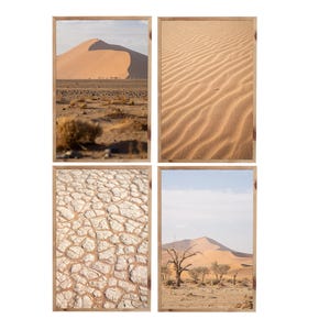 Könnte beinhalten: Vier gerahmte Drucke mit Wüstenlandschaften. Einer zeigt eine große Sanddüne, ein anderer welligen Sand, ein dritter rissige Erde und der letzte eine Düne mit spärlichen Bäumen. Die Rahmen sind hellbraun.