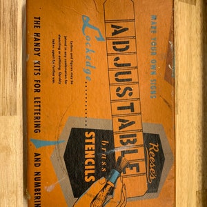 Könnte beinhalten: Eine Vintage-Schachtel mit Reese's Adjustable Stencils, mit einer Hand, die einen Pinsel hält, und dem Text "Machen Sie Ihre eigenen Schilder". Die Schachtel ist orange und braun mit den Worten "Lockedge" und "Messing-Schablonen" darauf gedruckt.
