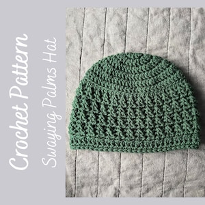 May include: A green crocheted hat with a textured stitch pattern. The hat is on a gray textured surface.