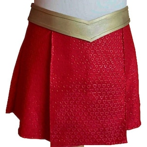 May include: A red skirt with a gold waistband. The skirt has a pattern of small triangles.