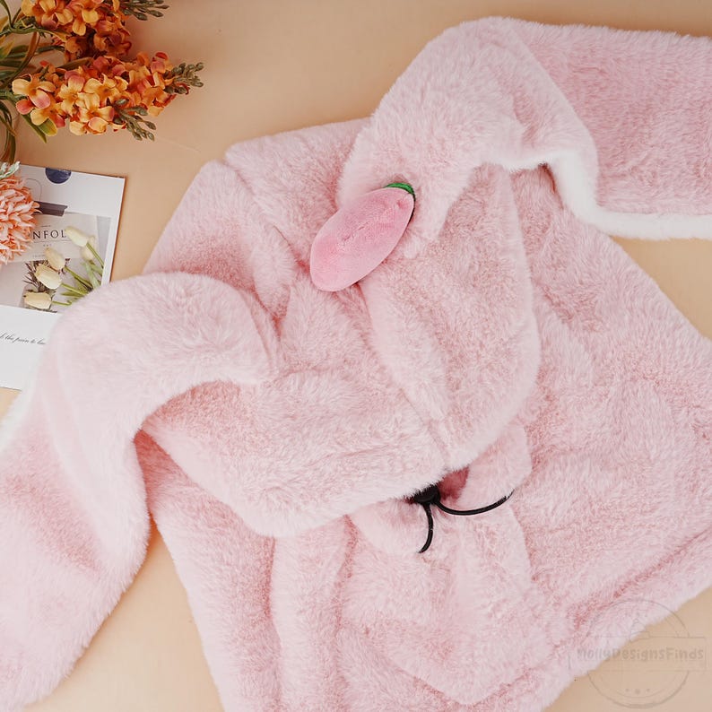 May include: A pink plush hooded jacket with a small pink plush strawberry attached to the hood.