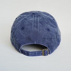 Pu&ograve; includere: Un cappellino da baseball blu navy con un aspetto sbiadito e consumato. Il retro presenta un cinturino regolabile con una fibbia in metallo color ottone. Il cappellino &egrave; realizzato in un tessuto morbido e strutturato.